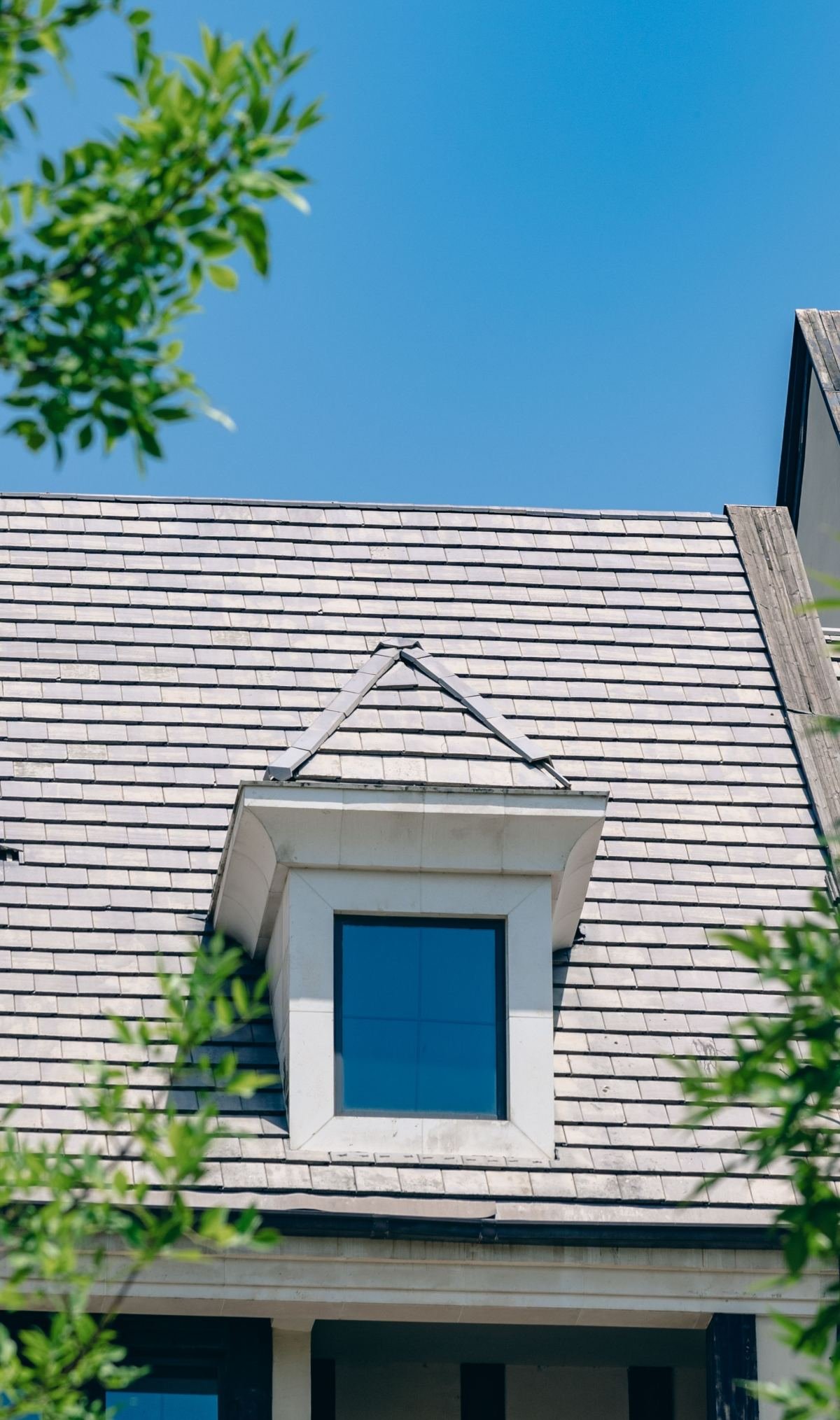 Close-up of a dormer window and architectural shingles on a pitched roof